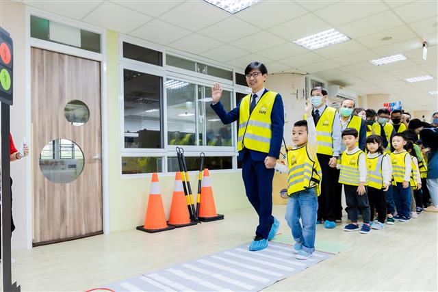 經濟部技術邱求慧處長(左)與西非營利幼兒園小朋友一同展示過馬路情境。