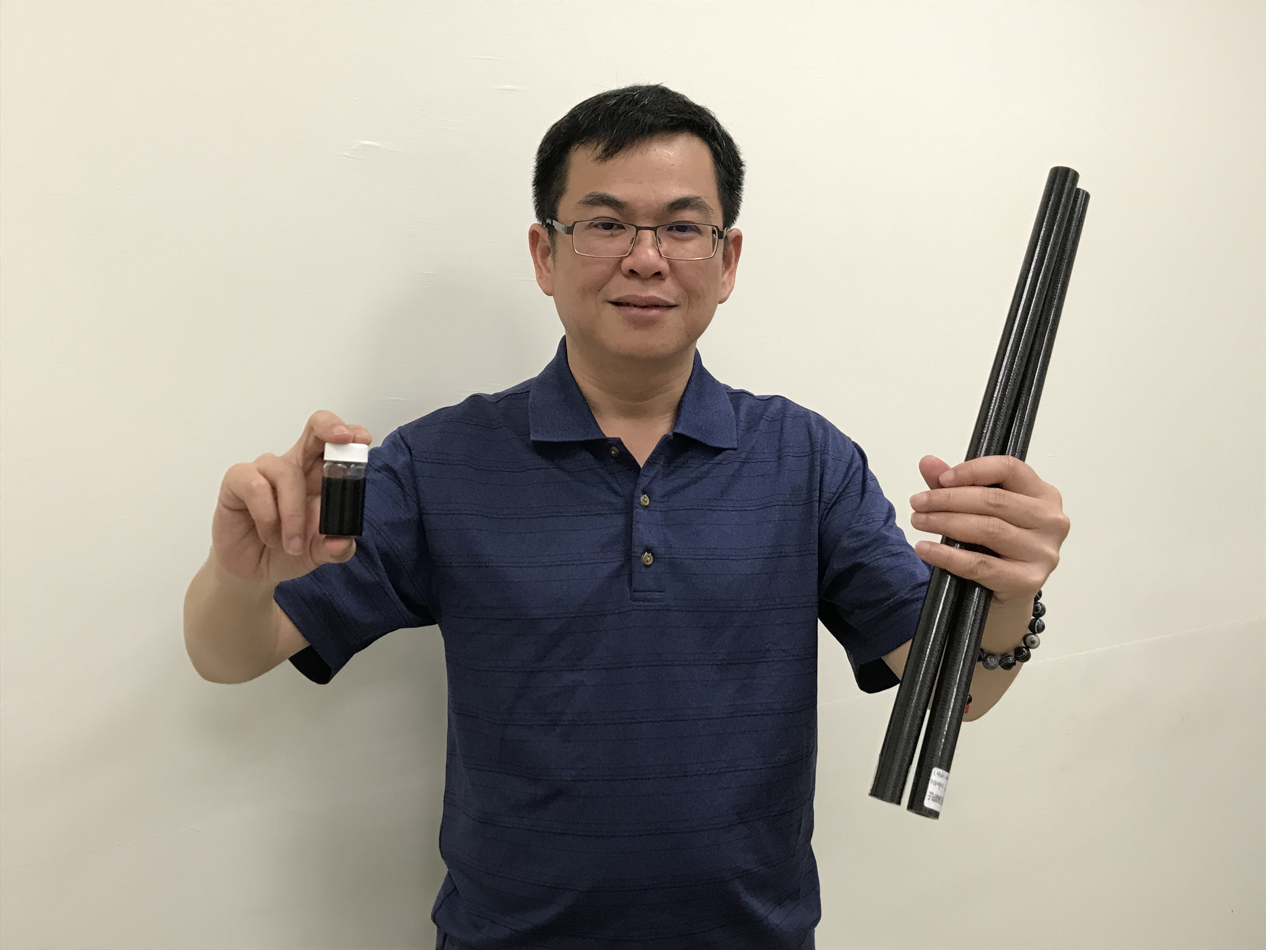 工研院材化所劉時州博士左手拿的是改質後的「胺基奈米碳管」粉末，右手則為以「輕量化高制振碳纖維複合材料」製成的產品