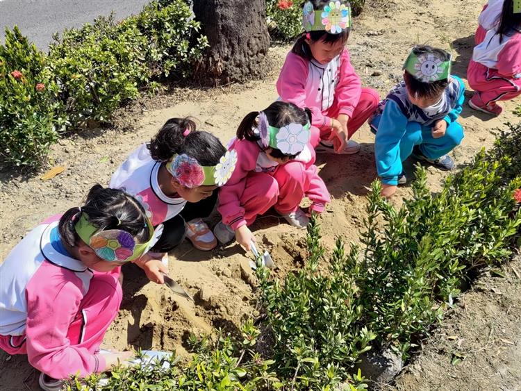 為響應植樹節，孩童在賣場旁花圃種下矮仙丹樹苗，推動環境教育向下扎根