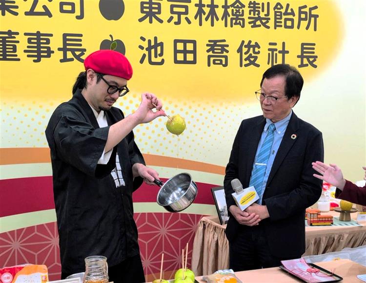東京林檎製飴所社長池田喬俊向台糖董事長吳明昌(右)展示蘋果糖製作手藝。