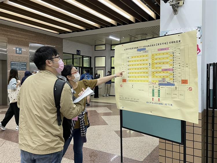 圖說：新進職員甄試登場，考生於入場前確認考場配置圖。