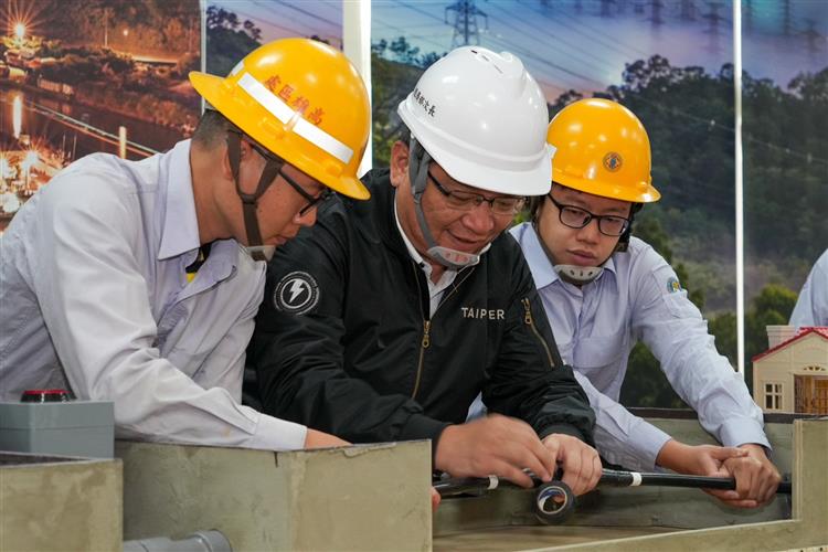 經濟部次長暨台電代理董事長曾文生體驗台電第一線人員現場搶修作業，親自操作配電地下電纜的壓接與絕緣處理作業。